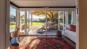 A room with a large sliding glass door leading to an outdoor patio with a table and chairs. - Waterside Bliss - Taupo Holiday Home (Taupo)