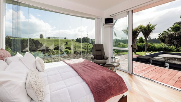 Une chambre avec un grand lit, une chaise et un téléviseur.