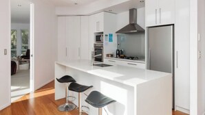 Une cuisine moderne avec des meubles blancs, des appareils en acier inoxydable et un îlot central doté de tabourets de bar.