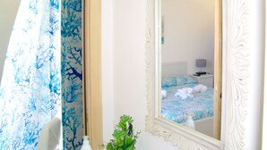 A bathroom with a mirror, a shower curtain, and a sink with a plant. - Lost in Amalfi, Your home in the heart of a peaceful village on the Amalfi Coast (Amalfi)