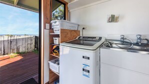 A compact kitchen with a washing machine, a sink, and a drying rack.