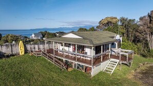 A coastal house with a deck, a kayak, and a view of the sea.