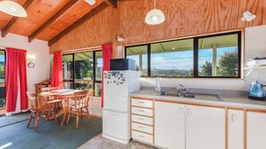 A kitchen with wooden cabinets, a refrigerator, a sink, and a window with a view of mountains.
