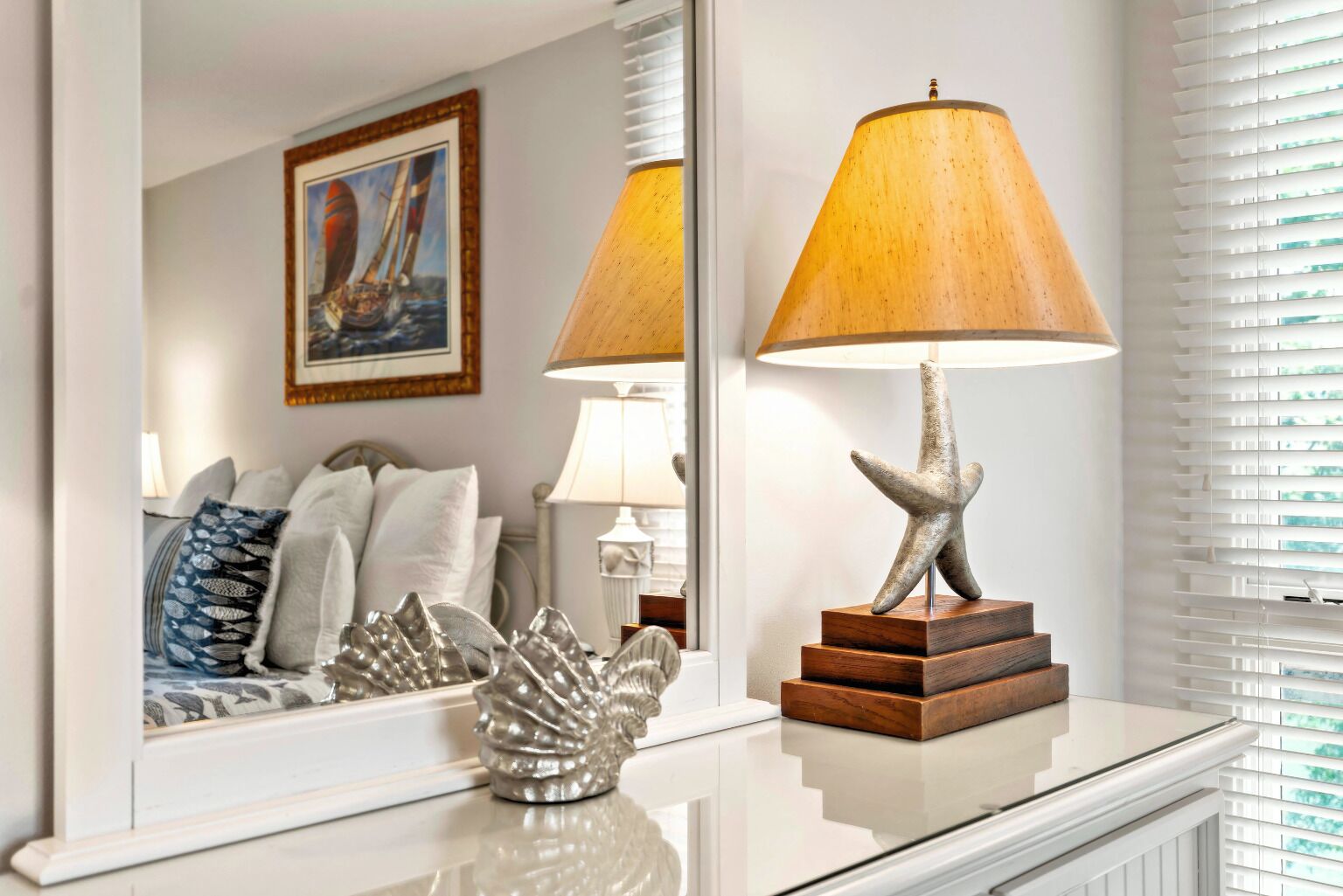 A well-lit room with a bed, a lamp, and a decorative starfish on a table.