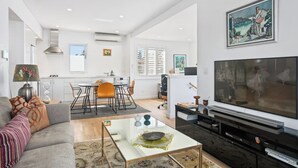 A modern living room with a sofa, coffee table, TV, and artwork.