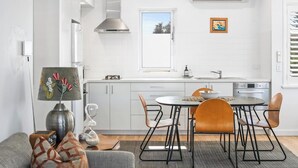 A modern kitchen with white cabinets, a dining table with four chairs, and a window with a view.