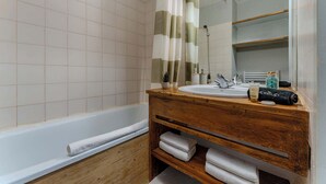 Une salle de bain avec un meuble-lavabo en bois, une baignoire blanche et un miroir.