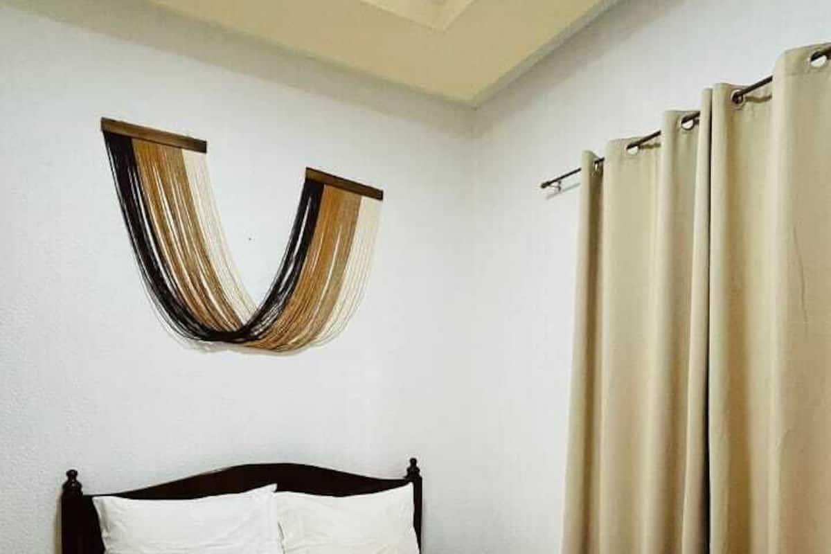 Un dormitorio con cama, cortinas y una decoración de pared original.