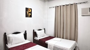 A hotel room with two beds, a ceiling light, a wall-mounted air conditioner, and a picture of flowers. - Cozy Stop Inn (Puerto Princesa)