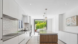 Una cucina moderna con mobili bianchi, una parete di fondo in vetro e un'isola in legno.