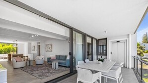 Un interno moderno con zona pranzo, divani e una porta vetrata che dà su uno spazio esterno.