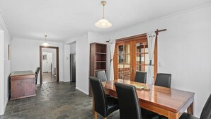 A dining area with a wooden table and black chairs, a stone floor, and a wooden cabinet.