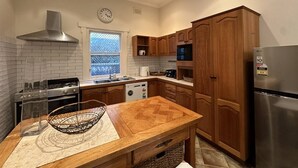 Une cuisine moderne avec des meubles en bois, un réfrigérateur en acier inoxydable et une table à manger en bois.