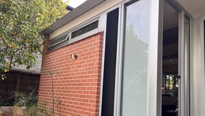 Ein modernes Gebäude mit Backsteinfassade, großen Schiebeglastüren und einem kleinen Fenster.