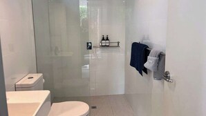 Ein modernes Badezimmer mit einer gläsernen Duschkabine, einer Toilette und einem Waschbecken.