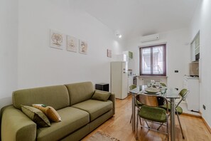 Un espacio habitable compacto con sofá, mesa de comedor, sillas y kitchenette.