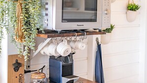 Une cuisine équipée d’une machine à café, d’un four à micro-ondes et agrémentée de plantes suspendues.