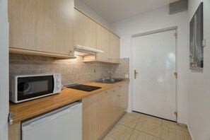 Una cocina con microondas, lavamanos y armarios de madera.