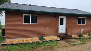 A two-story log cabin with a front door, two windows, and a small porch. - 3-bedroom Cabin at West Wind Resort in beautiful Waskish, MN on Upper Red Lake. (Waskish)