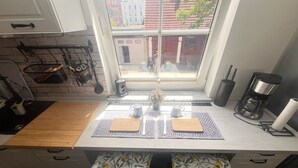 Et køkken med udsigt fra vinduet, en kaffemaskine og et bord med servietter.