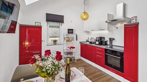 Een moderne keuken met rode kastjes, een inbouwoven en een hanglamp.