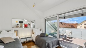 Een moderne slaapkamer met twee bedden, een grote spiegel en een balkon met een tafel en stoelen.