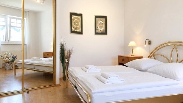 A hotel room with a bed, a nightstand, a lamp, a mirror, and two framed pictures on the wall. - Ferienwohnung Villy Seepark – mit Balkon & Parkplatz (Heringsdorf)