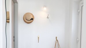 Ein Flur mit Fliesenboden, einem an der Wand befestigten Hut, einer Wandleuchte und einem hängenden Korb.