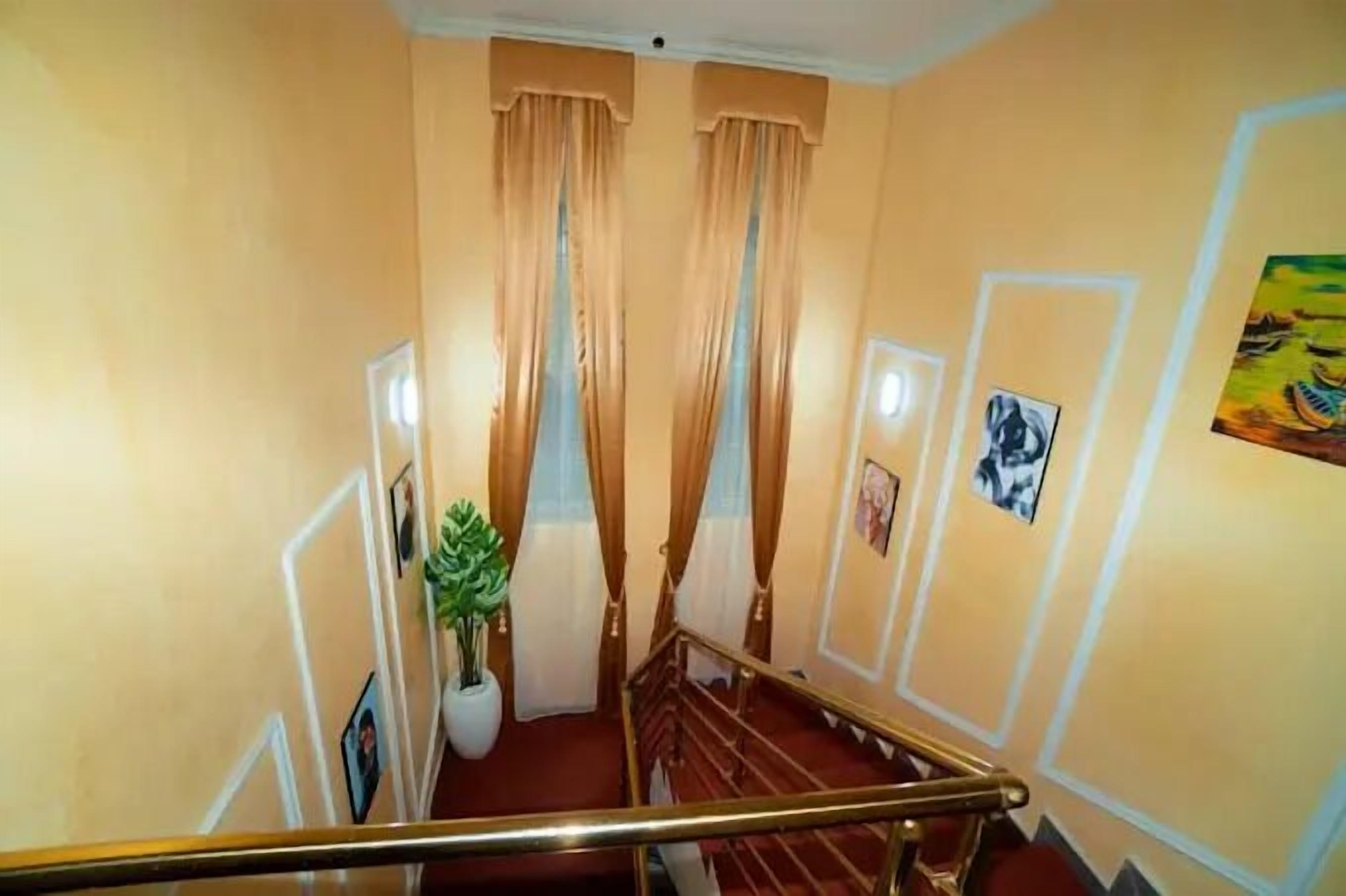 Eine Treppe mit rotem Teppich, beigen Wänden und einer Zimmerpflanze.