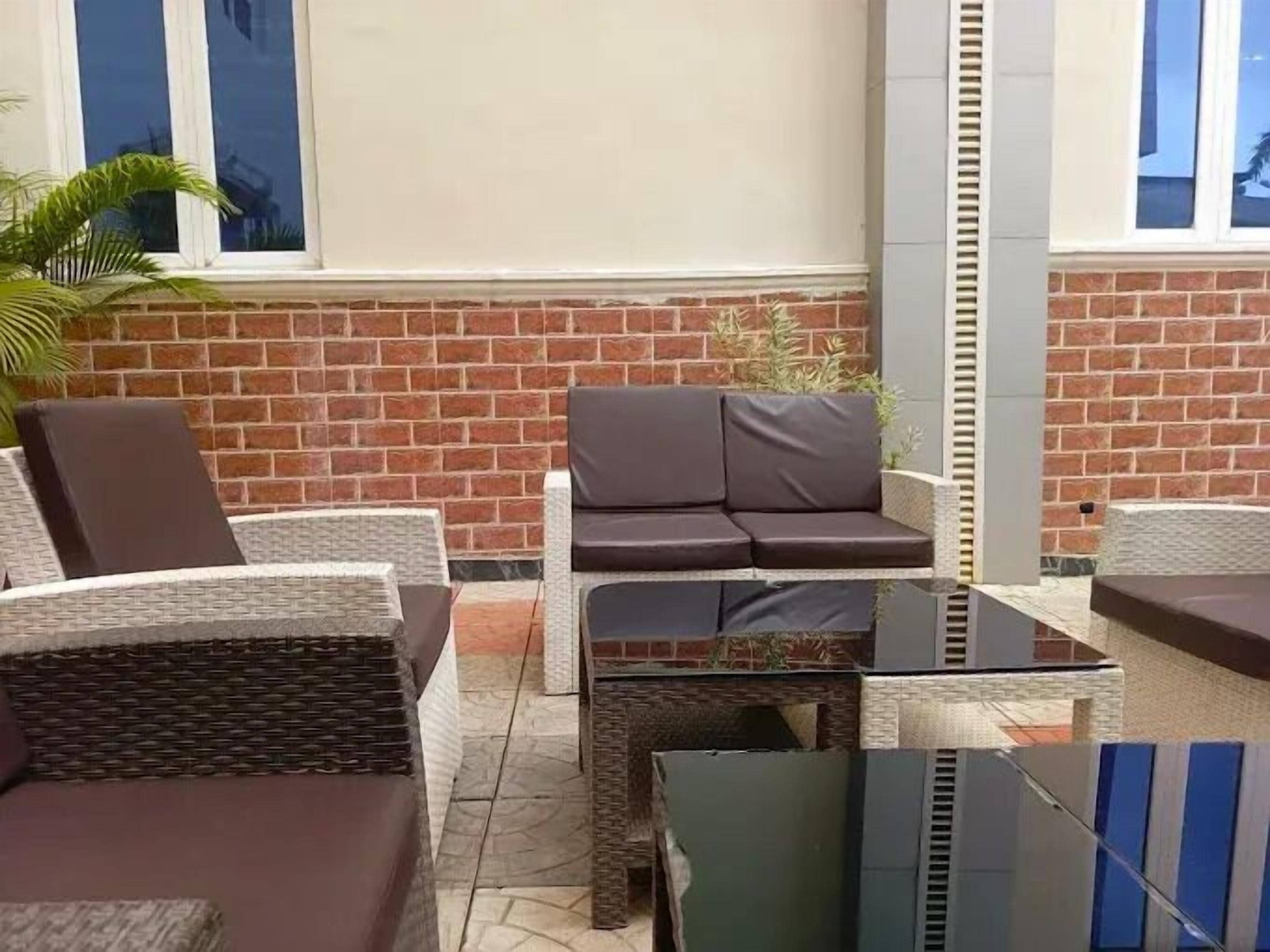 An outdoor seating area with wicker furniture and a brick wall backdrop.