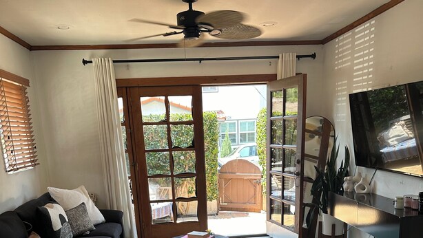 A living room with a black sofa, a round coffee table, a TV, and a sliding glass door leading to a patio. - North Pacific Beach - a cozy, 1-bedroom designed for rest, & recharge. (San Diego)