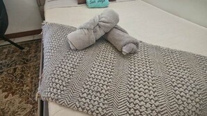 A neatly made bed with a grey blanket and a pillow labeled "San Diego." - North Pacific Beach - a cozy, 1-bedroom designed for rest, & recharge. (San Diego)
