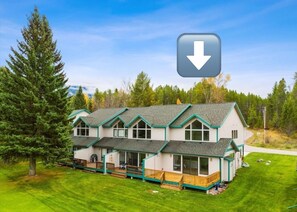 A multi-story house with a green roof, multiple decks, and a well-maintained lawn. - West Glacier Getaway: Mountain & Golf Course Views (West Glacier)