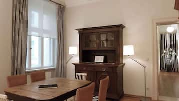 Un comedor con una mesa y sillas de madera, un aparador de madera oscura con puertas de cristal y dos lámparas de pie.