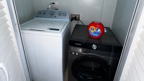 Un lavadero pequeño con lavadora, secadora y una unidad de lavadora-secadora apilada.