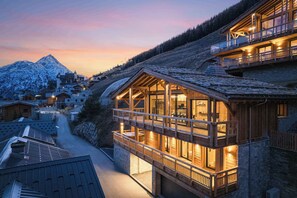 Una cabaña de madera con balcón que da a una montaña nevada.