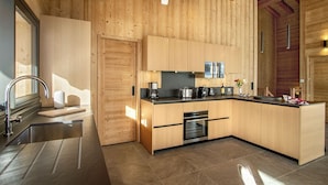 Una cocina moderna con paredes de madera, electrodomésticos de acero inoxidable y una encimera negra.
