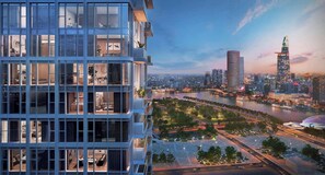 Un immeuble moderne de grande hauteur, doté de nombreux balcons et de grandes fenêtres, qui offre une vue sur une rivière et sur un paysage urbain ponctué d’imposants gratte-ciel.
