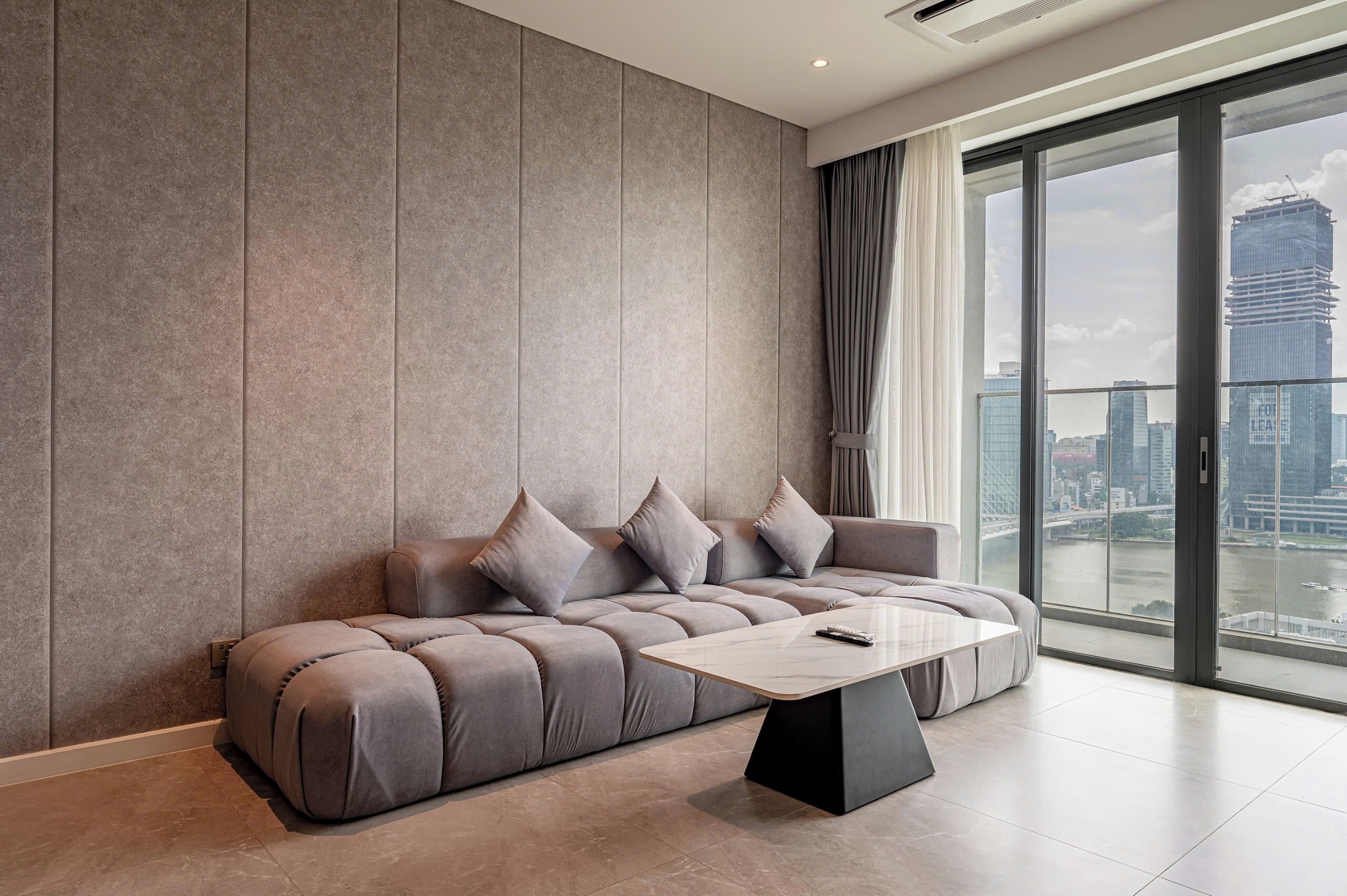 Una sala moderna con un sofá modular, una mesa de centro y un amplio ventanal con vistas a la ciudad.