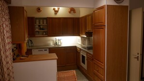 A compact kitchen with wooden cabinets, a microwave, a stove, and a sink. - Cozy Family Home With Lovely Garden (Kamperland)
