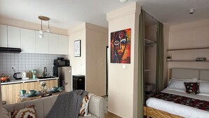 A modern apartment with a kitchen, a living area with a sofa and a bed, and a dining area. - Wakih homes! Cozy studio, 15 mins away from JKIA and 7 minutes away from SGR (Nairobi)
