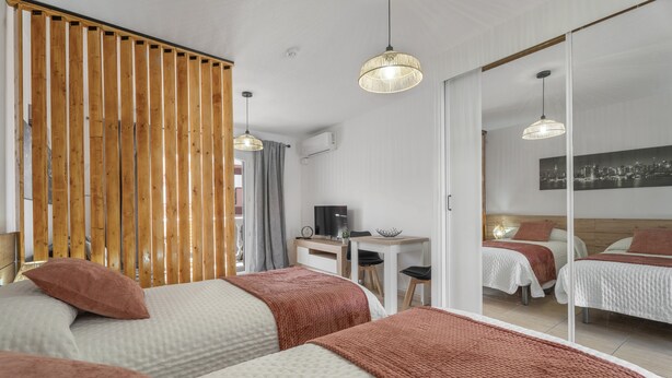 Ein Hotelzimmer mit zwei Betten, einem Schreibtisch, einem Stuhl, einem Fernseher und einem großen Spiegel.
