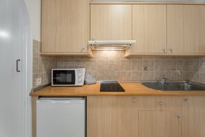 A kitchen with wooden cabinets, a microwave, a toaster, a sink, and a dishwasher.