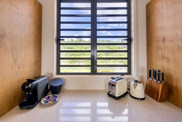 A kitchen with a window, a coffee maker, a toaster, and a knife block.