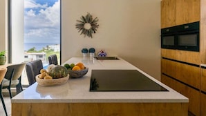 Una cocina moderna con una isla grande, vistas al mar y una pared de acento de madera.