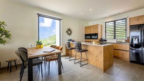 Una cocina moderna con una isla central, taburetes de bar y una mesa de comedor con sillas.