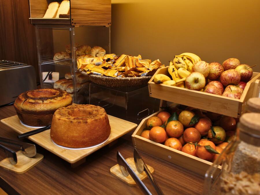 A breakfast buffet with various baked goods, fruits, and a bread basket.