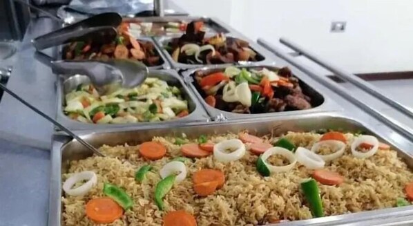 A buffet with various dishes including rice, vegetables, and meat.