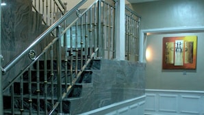 Un escalier en marbre avec des rampes métalliques menant à l’étage supérieur.