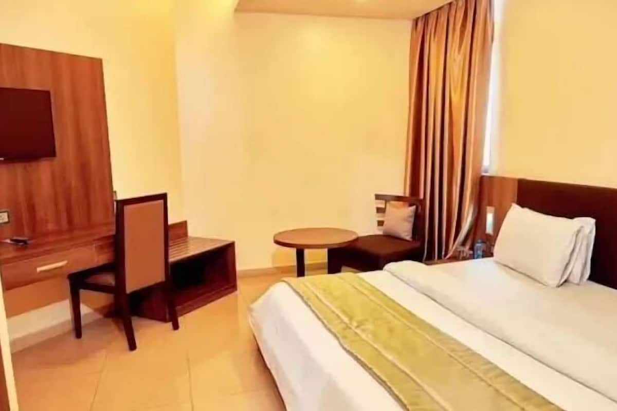 Una habitación de hotel con una cama, un escritorio, una silla, un televisor y una pequeña mesa.